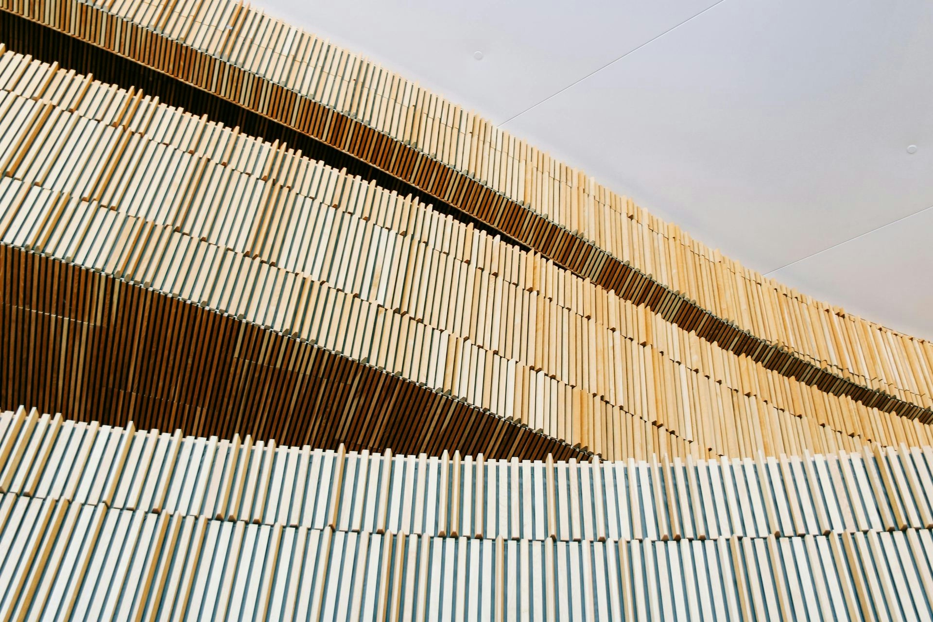 From below of geometric minimalist wooden construction under white ceiling in modern building