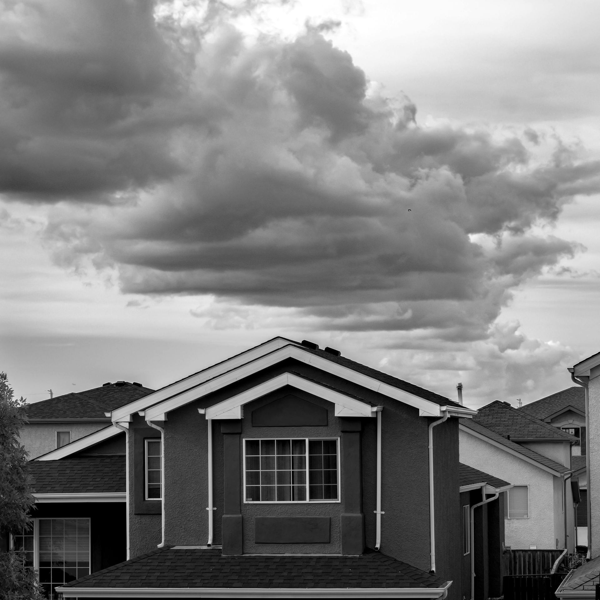 Grayscale Photo of a House Under Cloudy Sky