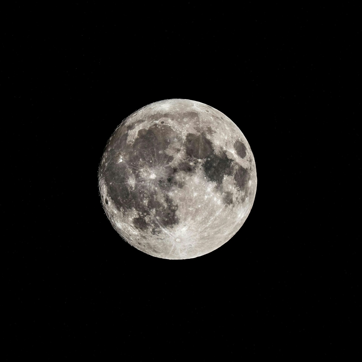 Low angle of black and white bright shiny full moon in dark night sky