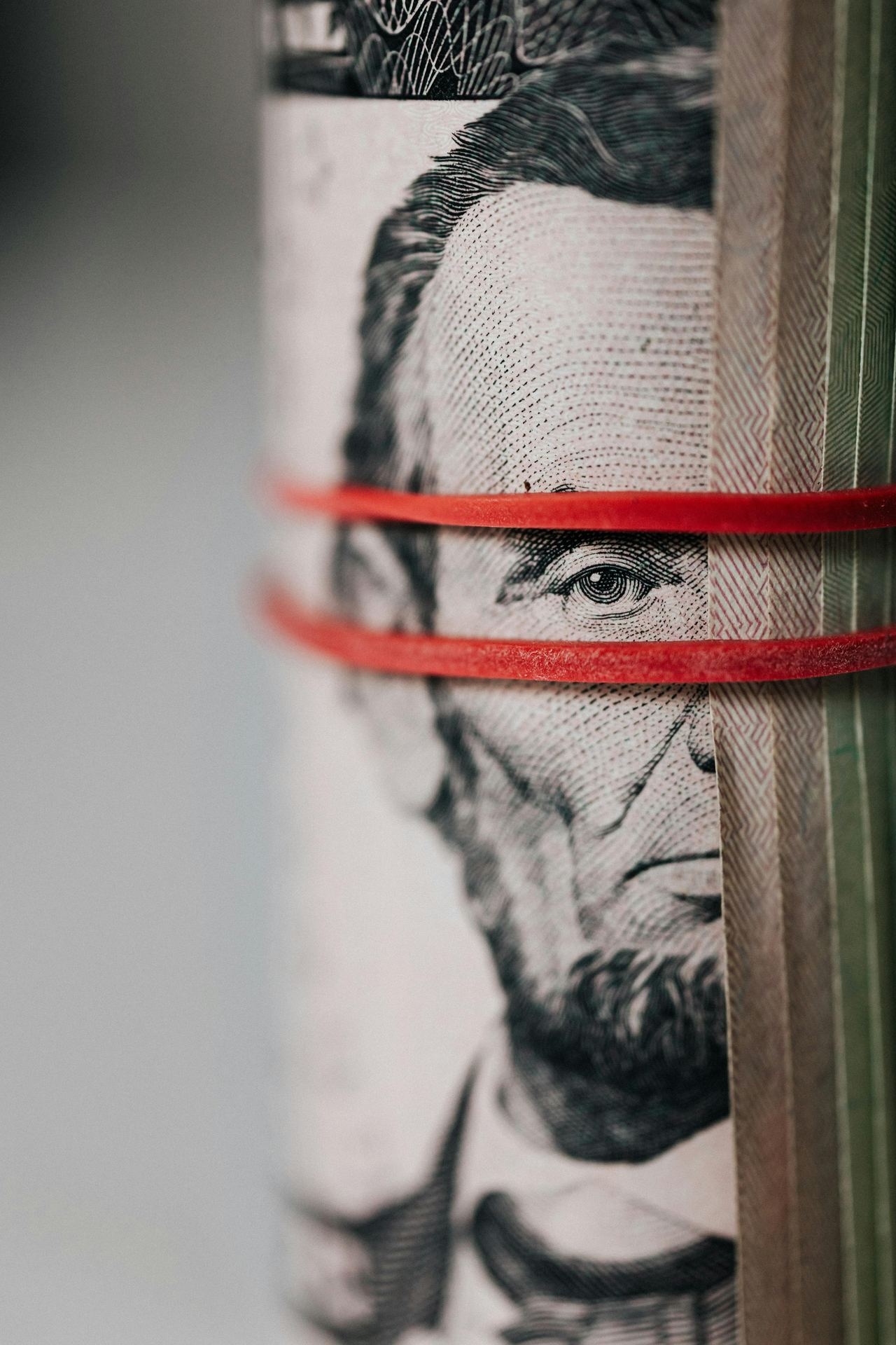 Closeup of rolled United States five dollar bills tightened with red rubber band