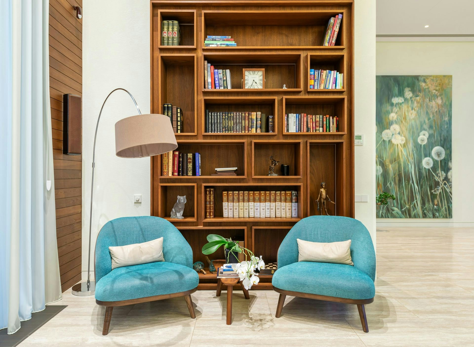 Living room with cozy chairs near lamp and wooden bookcase