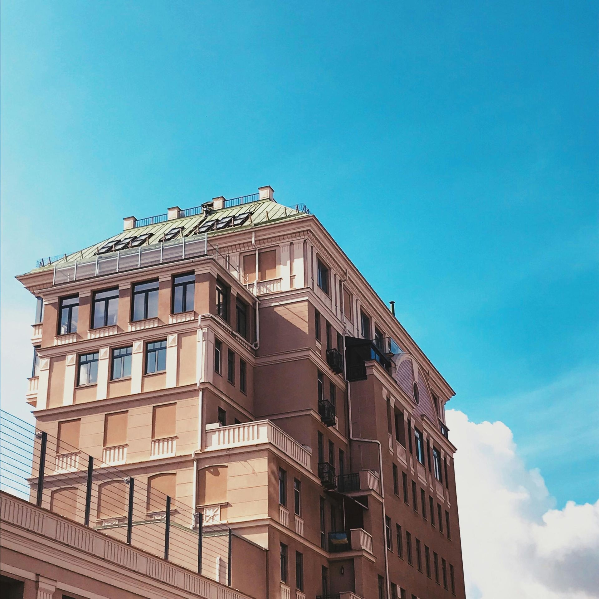 From below of building facade with metal fence below under clear blue sky