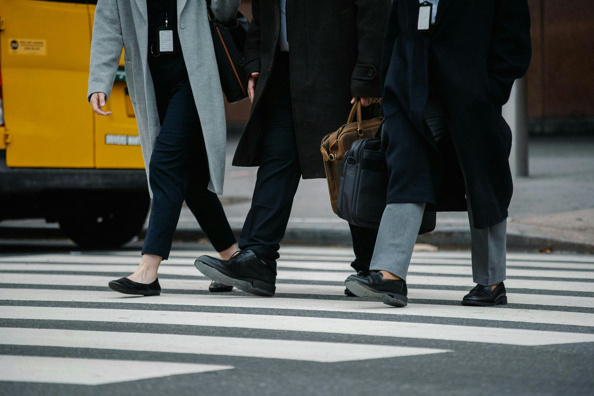 Crop faceless colleagues walking on crossroad in city