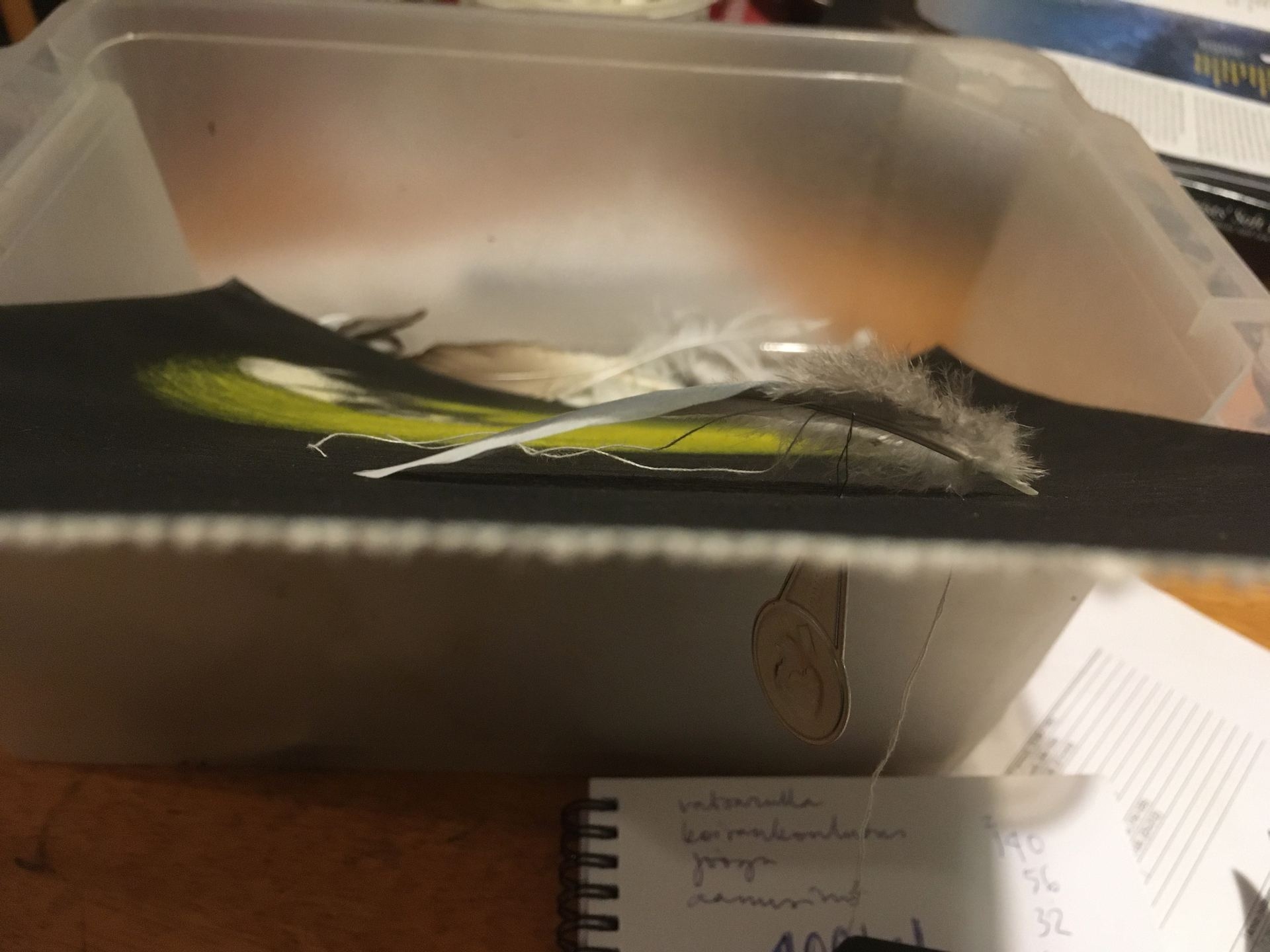 My mom's old sowing kit has a handy helper to pull the yarn from under the feather where a needle doesn't fit.