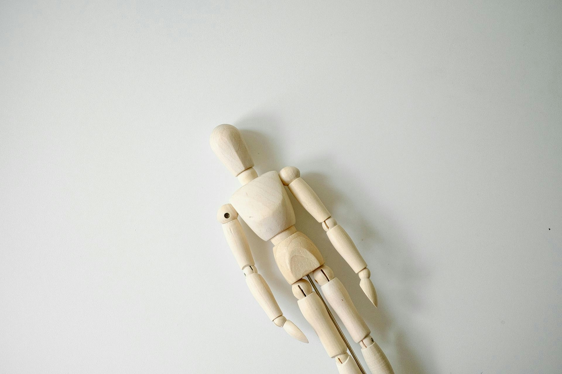 A wooden mannequin on a white surface