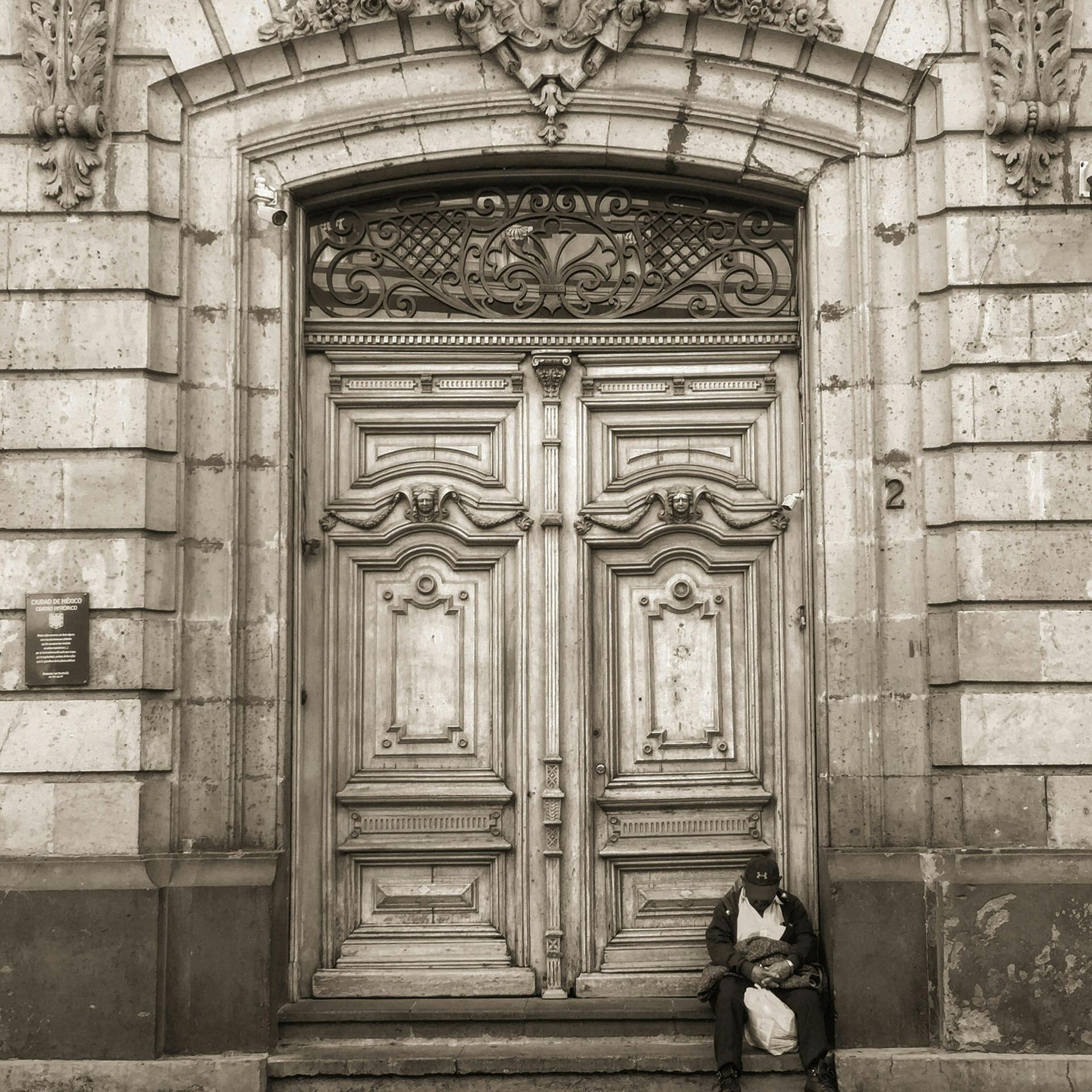 Man Sitting at the Entrance of a Building