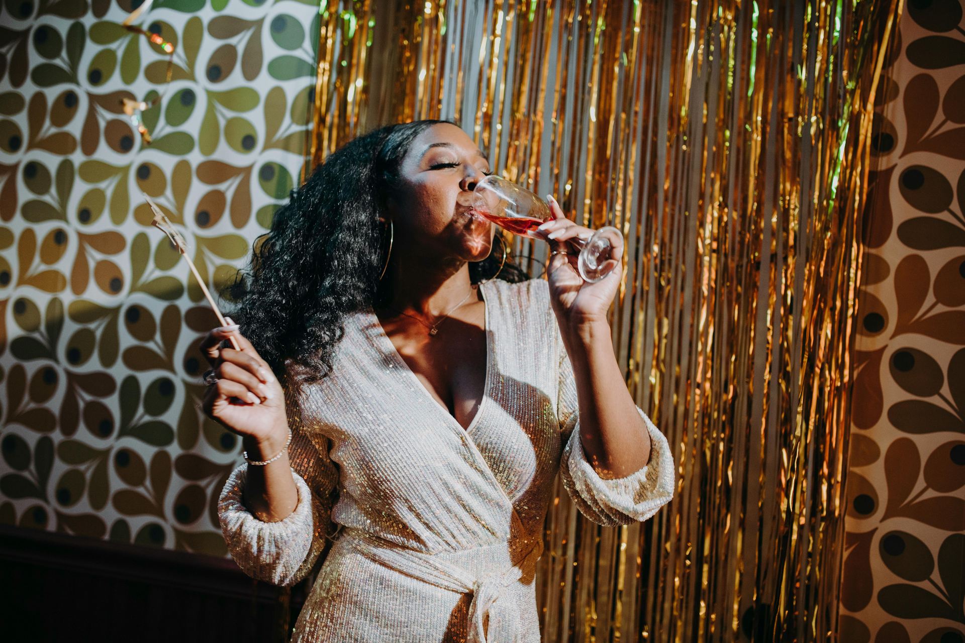 A woman joyfully toasts with champagne at a festive indoor party.