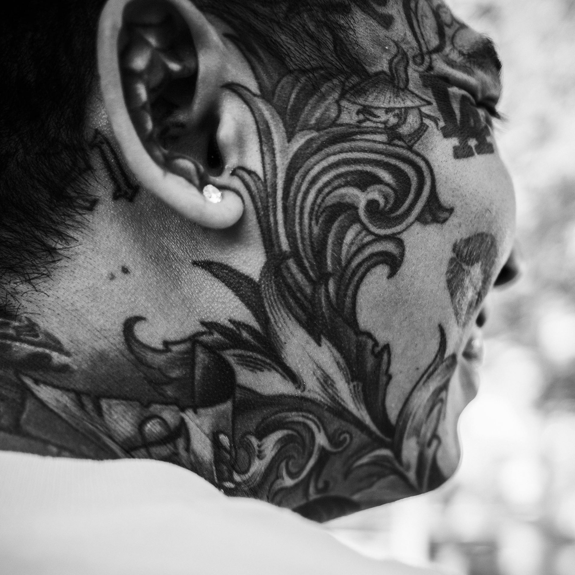 Black and white cheerful ethnic guy with ornaments tattooed on face resting in city