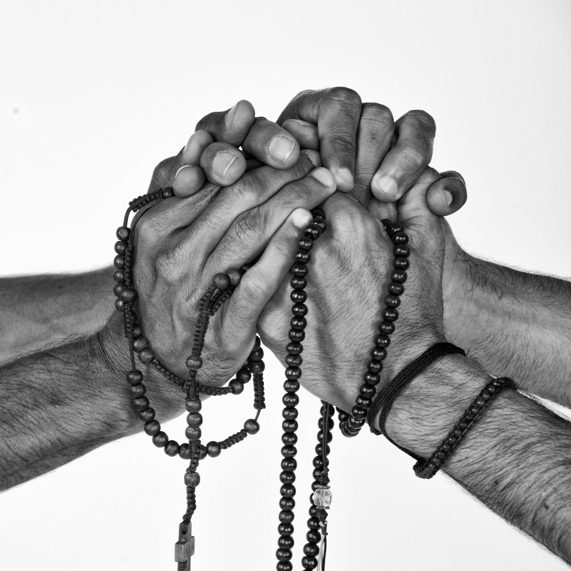 Hands of four men holding rosary beads