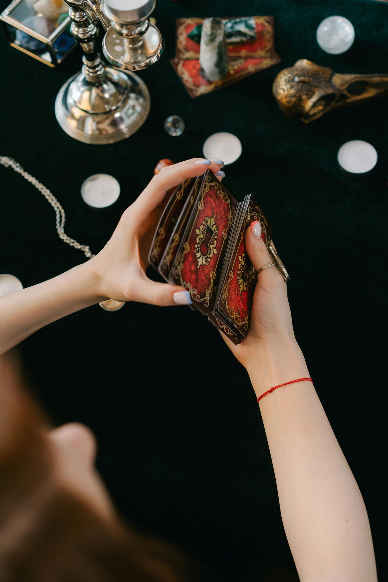 Anonymous female fortune teller shuffling tarot cards at table