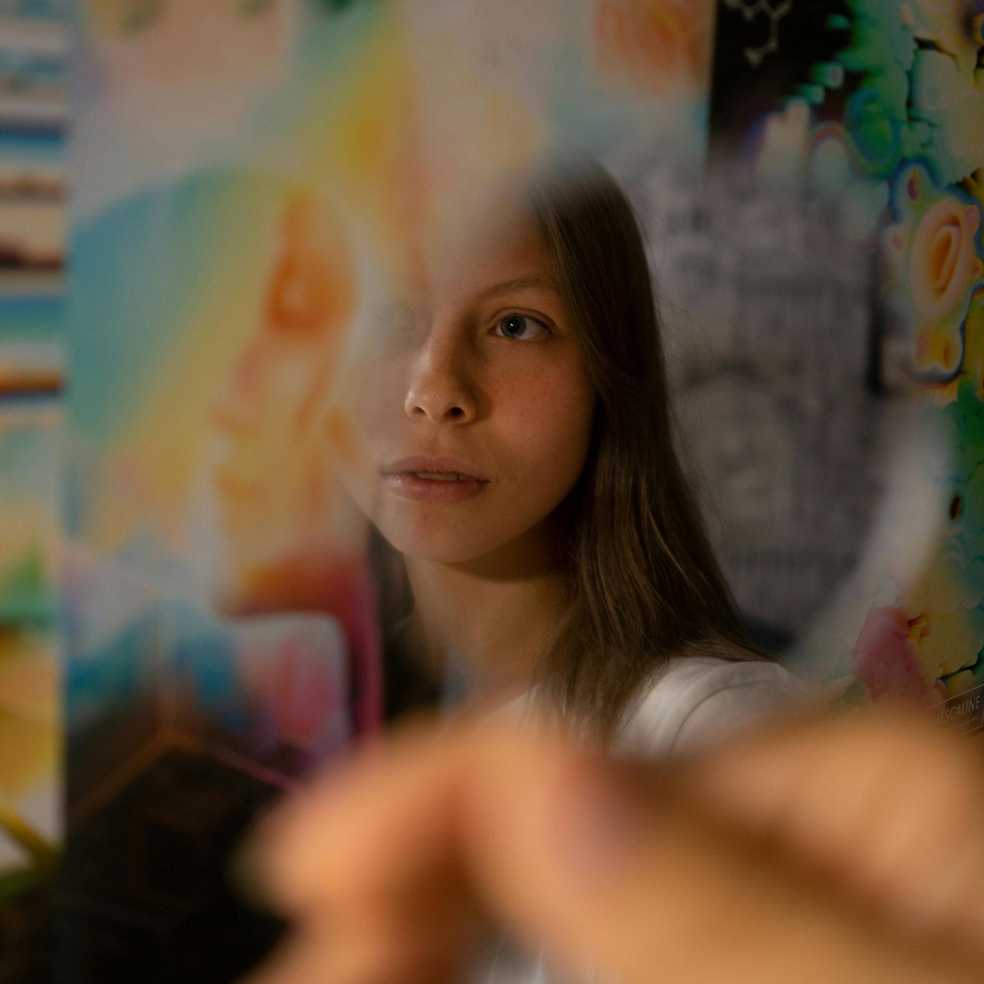 Artful composition of a woman gazing through a prism with vibrant reflections indoors.